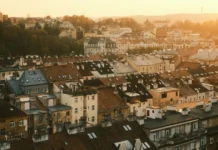 Starší betonový bytový dům se žaluzií na oknech a opotřebeným vchodem