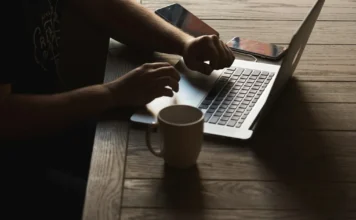 Pracovní stůl s notebookem, šálkem kávy a papíry s finančními údaji