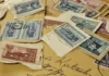 Investice do poštovních známek: vyplatí se filatelie? Staré album s poštovními známkami otevřené na starožitném stole v měkkém okénním světle, rozházené známky a písemnosti vedle něj