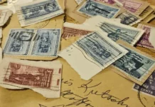 Investice do poštovních známek: vyplatí se filatelie? Staré album s poštovními známkami otevřené na starožitném stole v měkkém okénním světle, rozházené známky a písemnosti vedle něj